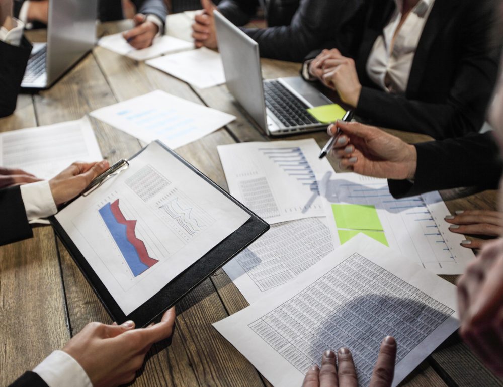 Business people analyzing financial documents showing income, charts and graphs, teamwork concept