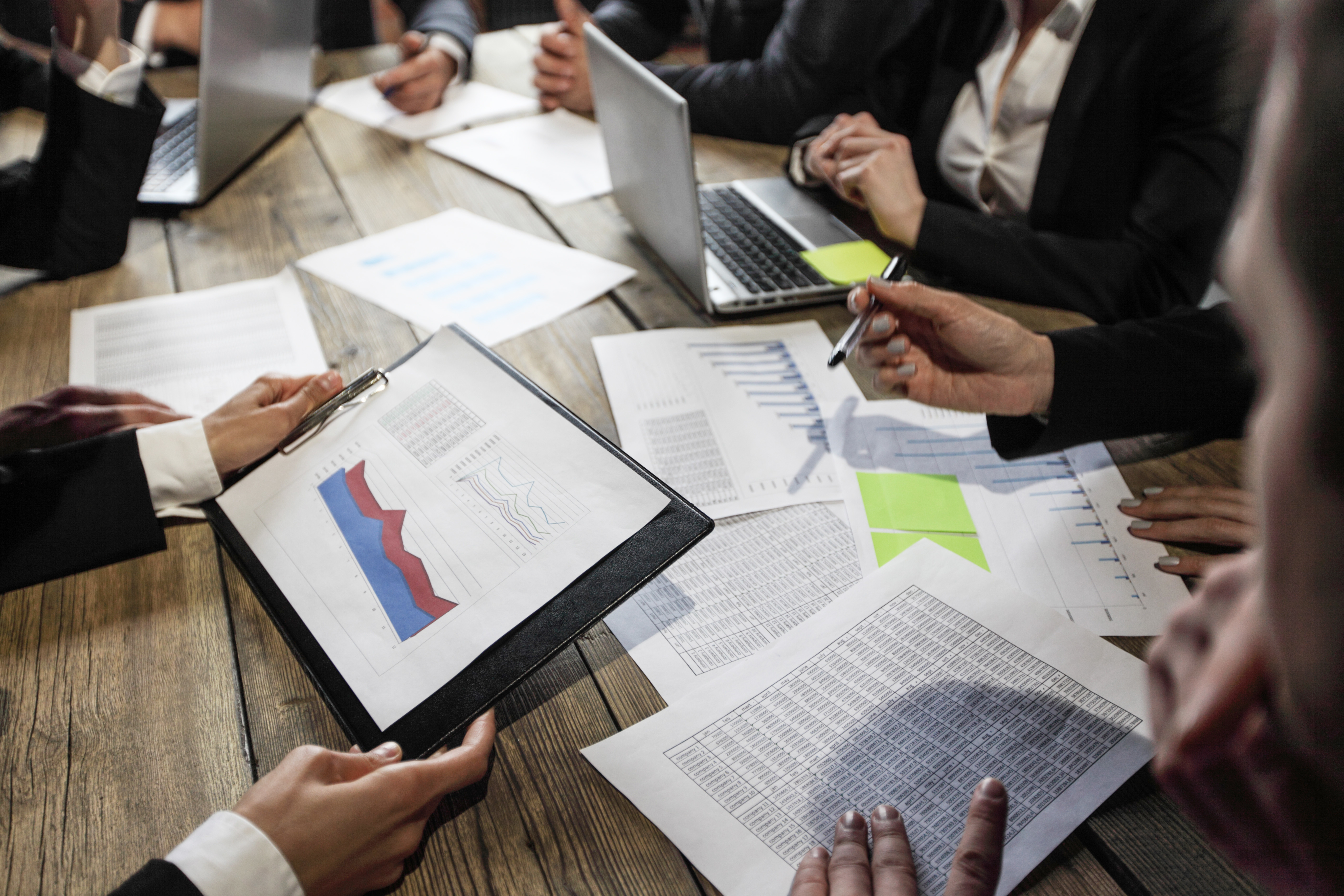 Business people analyzing financial documents showing income, charts and graphs, teamwork concept